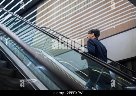 Handsome man standing on escalator Stock Photo