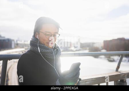 Handsome man with smartphone on footbridge Stock Photo