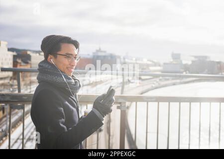 Handsome man with smartphone on footbridge Stock Photo