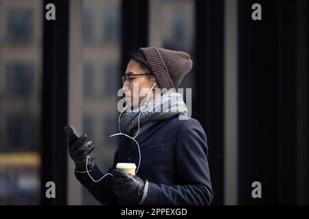 Handsome man with smartphone and paper cup on street Stock Photo