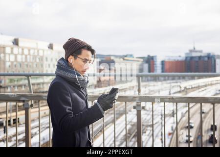 Handsome man with smartphone on footbridge Stock Photo