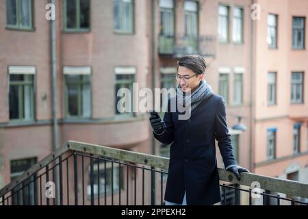 Handsome man with smartphone on footbridge Stock Photo