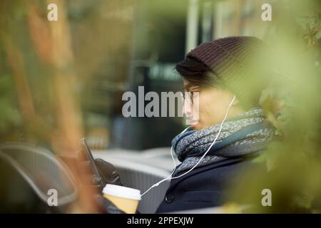 Man using cell phone in outdoor cafe Stock Photo