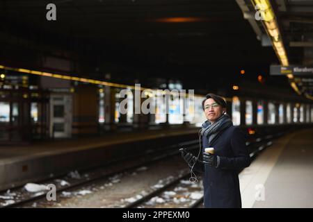 Smiling man standing at train platform Stock Photo