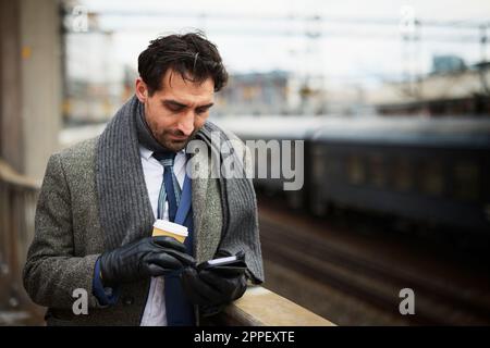 Businessman using phone at train station Stock Photo