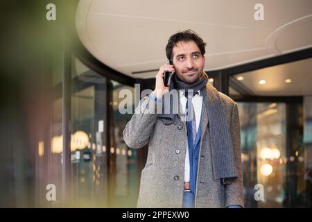 Businessman talking on phone outdoors Stock Photo