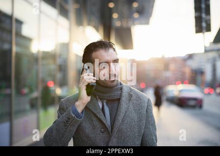 Businessman talking on phone outdoors Stock Photo