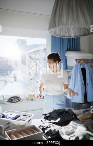 Woman folding clothes on bed Stock Photo