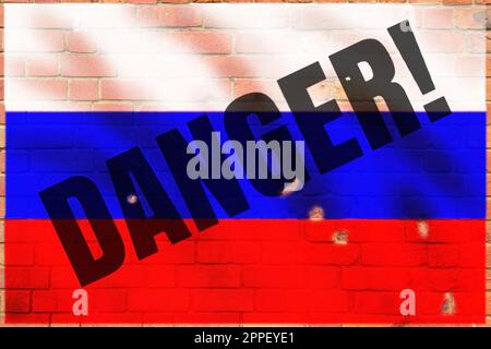 The flag of russia is painted on a brick wall. Danger text. Toxicity sign. Flag on an old stone wall. Stock Photo