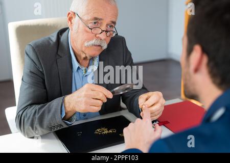 man checking diamond through magnifying loupe Stock Photo