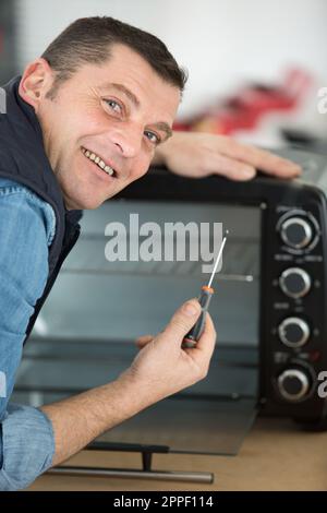 man repairing microwave oven in kitchen Stock Photo
