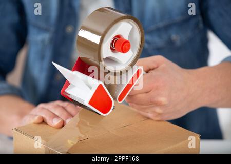 photo of a womans hands taping up a cardboard box Stock Photo