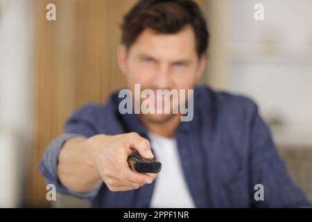 man changes the channels on the remote control Stock Photo