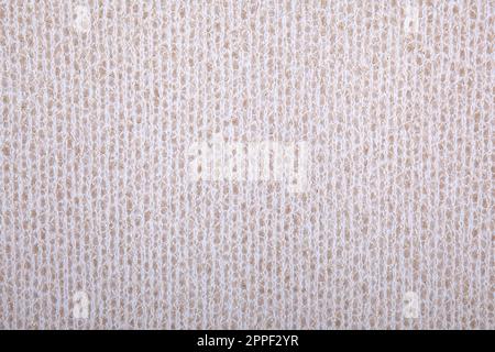 Knitted background. Knitted wallpaper. Beige, light geige knitted fabric. Knitted texture. Soft material. Brown, beige and white close up photo Stock Photo