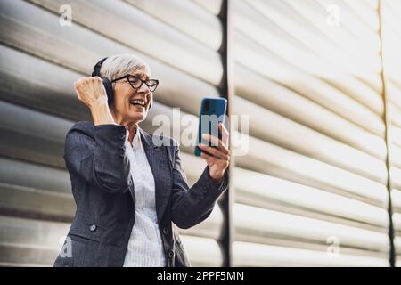 Outdoor portrait of successful mature businesswoman who is using smartphone on break at work. Stock Photo