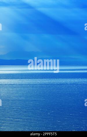 Morning sunlight beaming through clouds at Kvarner gulf of Adriatic sea in Croatia Stock Photo