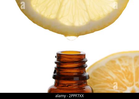Dripping lemon essential oil from into bottle isolated on white Stock Photo