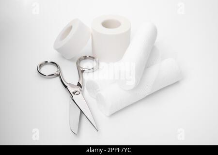 Medical bandage rolls, sticking plaster and scissors on white wooden ...