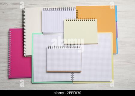 Many different notebooks on white wooden table, flat lay Stock Photo