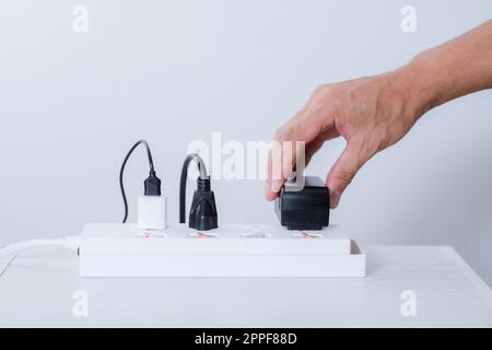 Closeup of a mans hand inserting a plug into electrical power strip. Stock Photo