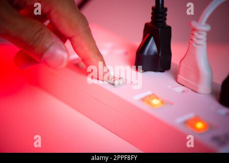 Close up a mans hand turn off the switch on power strip. Stock Photo
