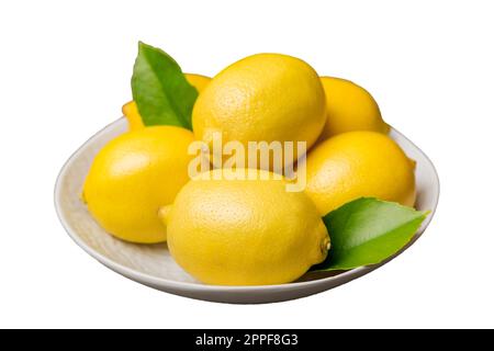 Fresh cutted lemon and whole lemons over round plate isolated on white background. Food and drink ingredients preparing. healthy eating theme top view Stock Photo