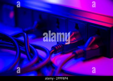 Many plugs connected to the black power strip. Stock Photo
