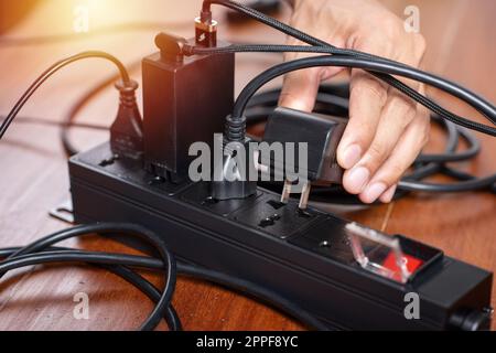 Closeup of a mans hand inserting a plug into electrical power strip. Stock Photo