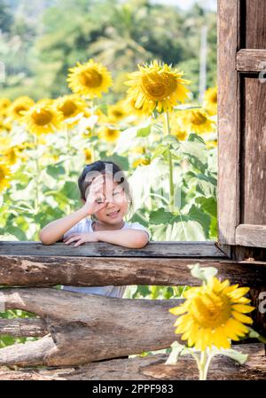 portrait of Asian adorable little girl in the  field of sunflowers (Helianthus annuus) Stock Photo