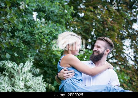 Happy young man carrying woman in garden, Bavaria, Germany Stock Photo