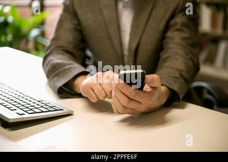 Mid section of a businessman using smart phone in an office, Bavaria, Germany Stock Photo