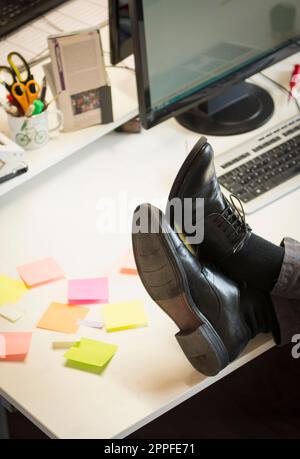 Low section of a businessman feet up on desk in an office, Bavaria, Germany Stock Photo