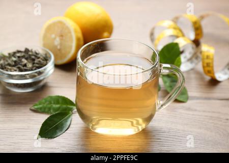 Herbal diet tea, lemon and measuring tape on wooden table Stock Photo