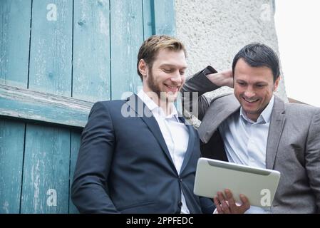 Two businessmen using digital tablet outside, Bavaria, Germany Stock Photo