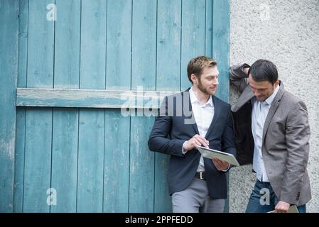 Two businessmen using digital tablet outside, Bavaria, Germany Stock Photo