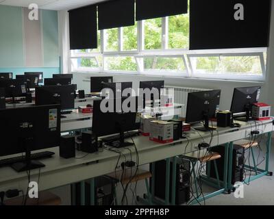 Sremska Mitrovica, Serbia, May 15, 2021 Group of computer neatly placed in a computer lab. Computers, monitors, wires in the modern classroom of the new school. School desks for pupils and students Stock Photo