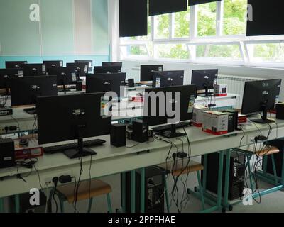 Sremska Mitrovica, Serbia, May 15, 2021 Group of computer neatly placed in a computer lab. Computers, monitors, wires in the modern classroom of the new school. School desks for pupils and students Stock Photo