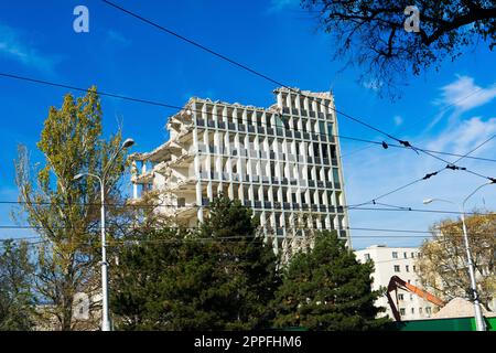 Demolition of the old building with sloopkraan against blue clouds sky. Stock Photo