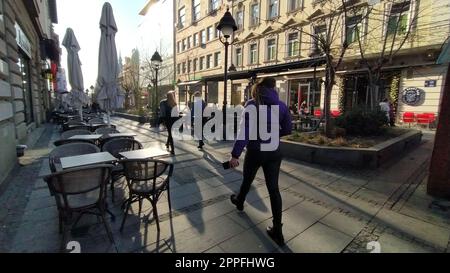 Belgrade, Serbia - January 24, 2020: morning street in the city center. People rush about their business. Street cafes are still closed. Tables, chairs and umbrellas. Girls walk energetically Stock Photo