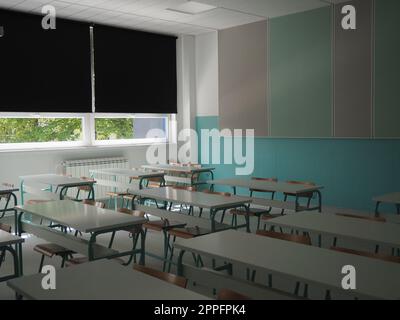 Lecture room with empty seats. Business seminar education. Modern new school. White furniture. Large windows with blackout curtains or blinds. Empty school classroom. Furniture and school equipment Stock Photo