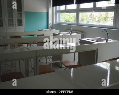 Chemistry room in a modern new school. Beautiful white furniture with sinks and washbasins. Large windows with blackout curtains or blinds. Empty school classroom. Furniture and school equipment Stock Photo