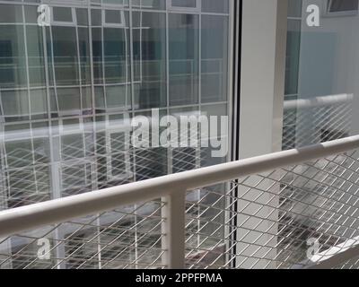 New white frames and windows. Metal fence for the safety of schoolchildren. New modern school. View from the window to the opposite wall and windows. Security systems. Internal office interior. Stock Photo