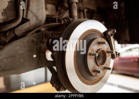 Car disc brake system. Car suspension in process of new tire replacement at garage workshop. Car disc brake mechanic check and repair. Disk break rotor. Car in change tire process at service station. Stock Photo