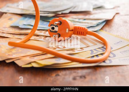 Electric plug and euro money on wooden table. Concept of increasing electric prices. Stock Photo