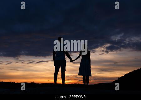 Couple standing holding hands at summer sunset Stock Photo
