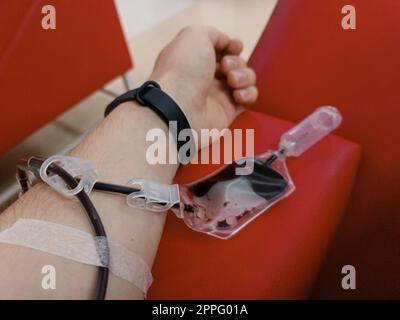 Blood donation, blood transfusion, check specified, fasting, health care. Left arm of caucasian young man with equipment for blood or plasma donations in donation centre. Blood donation concept. Plasma donation concept. Save life concept. Stock Photo