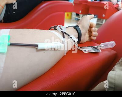 Blood donation, blood transfusion, check specified, fasting, health care. Left arm of caucasian young man with equipment for blood or plasma donations in donation centre. Blood donation concept. Plasma donation concept. Save life concept. Stock Photo