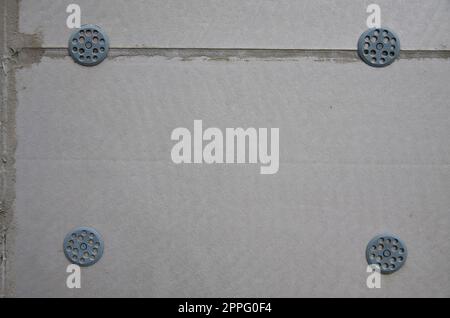 The texture of the wall, covered with gray foam polystyrene plates, which are reinforced with plastic umbrella dowels. Stage of wall insulation Stock Photo