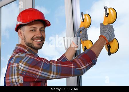 Worker using suction lifters during plastic window installation indoors Stock Photo