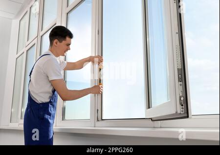 Worker using bubble level after plastic window installation indoors Stock Photo